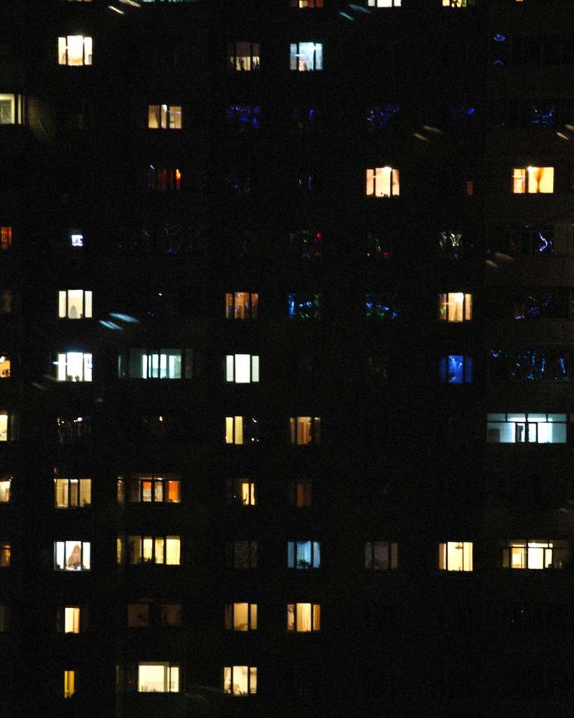 Apartment block at night with a few lit windows