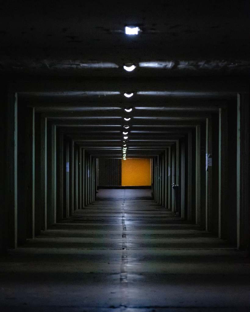 Long dark corridor with a lit door at the far end